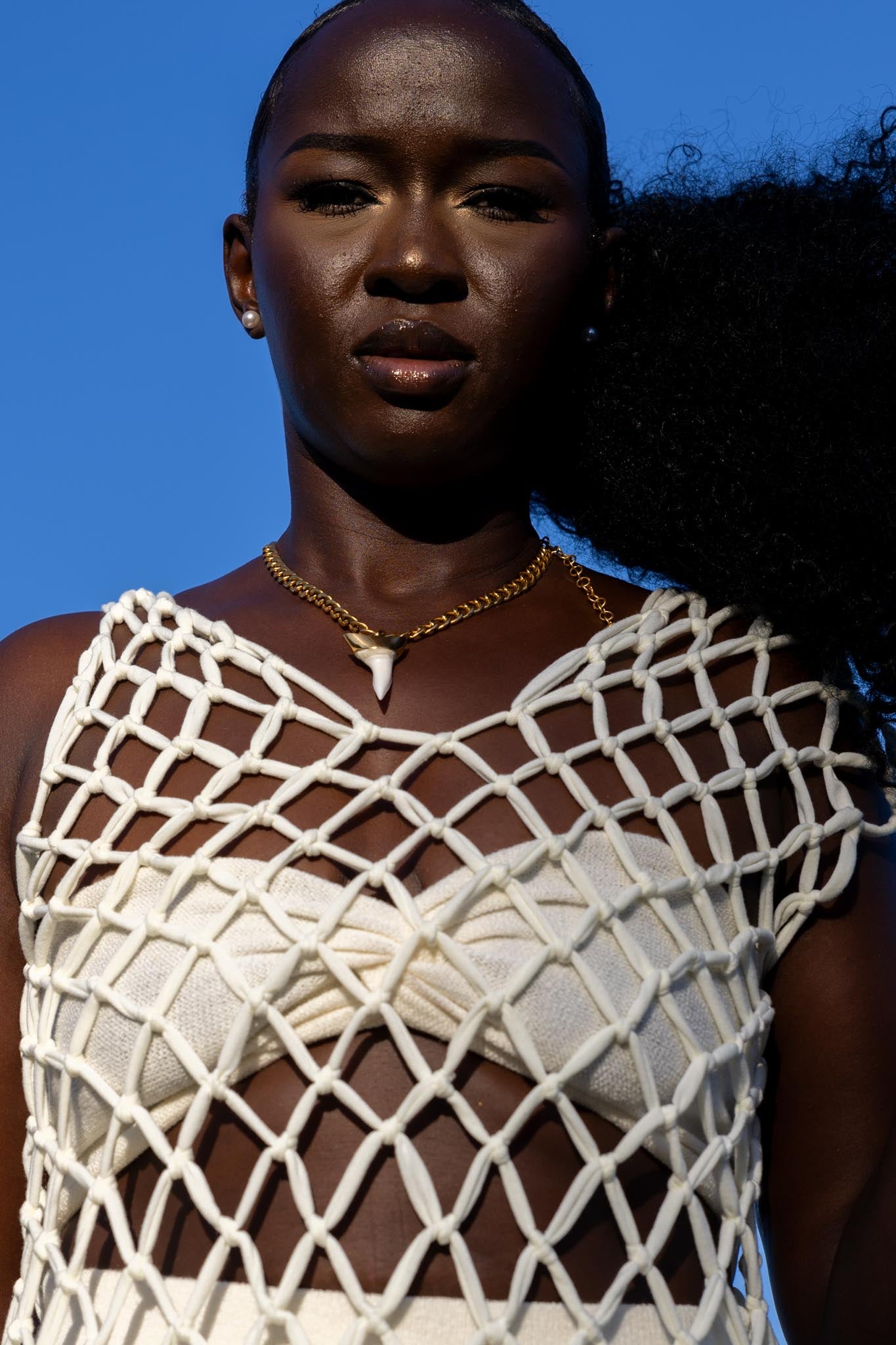 Model wearing Zokkibee shark tooth necklace with gold chain styled for modern, bold fashion