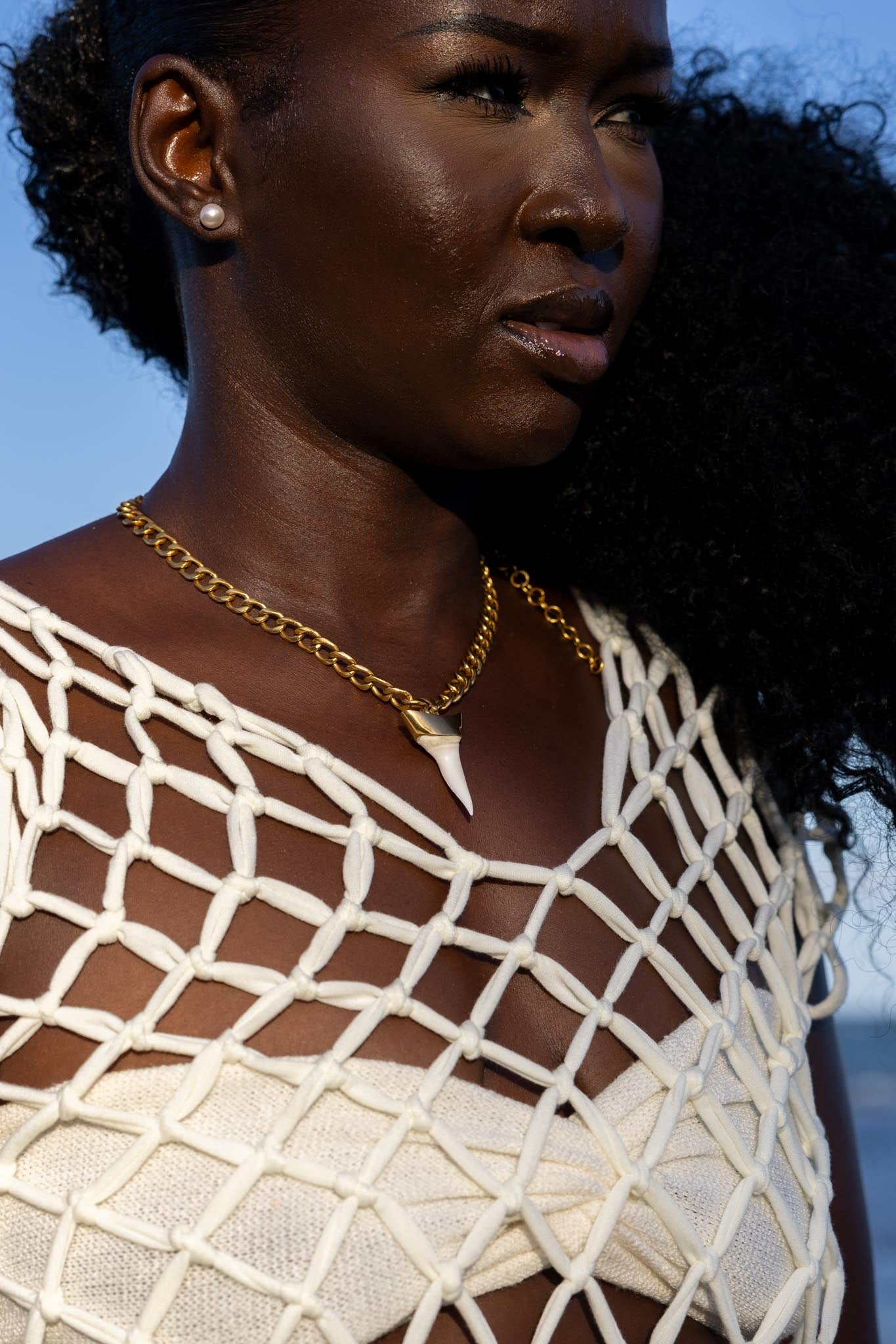 Side angle of Zokkibee shark tooth necklace highlighting shark tooth pendant and gold chain